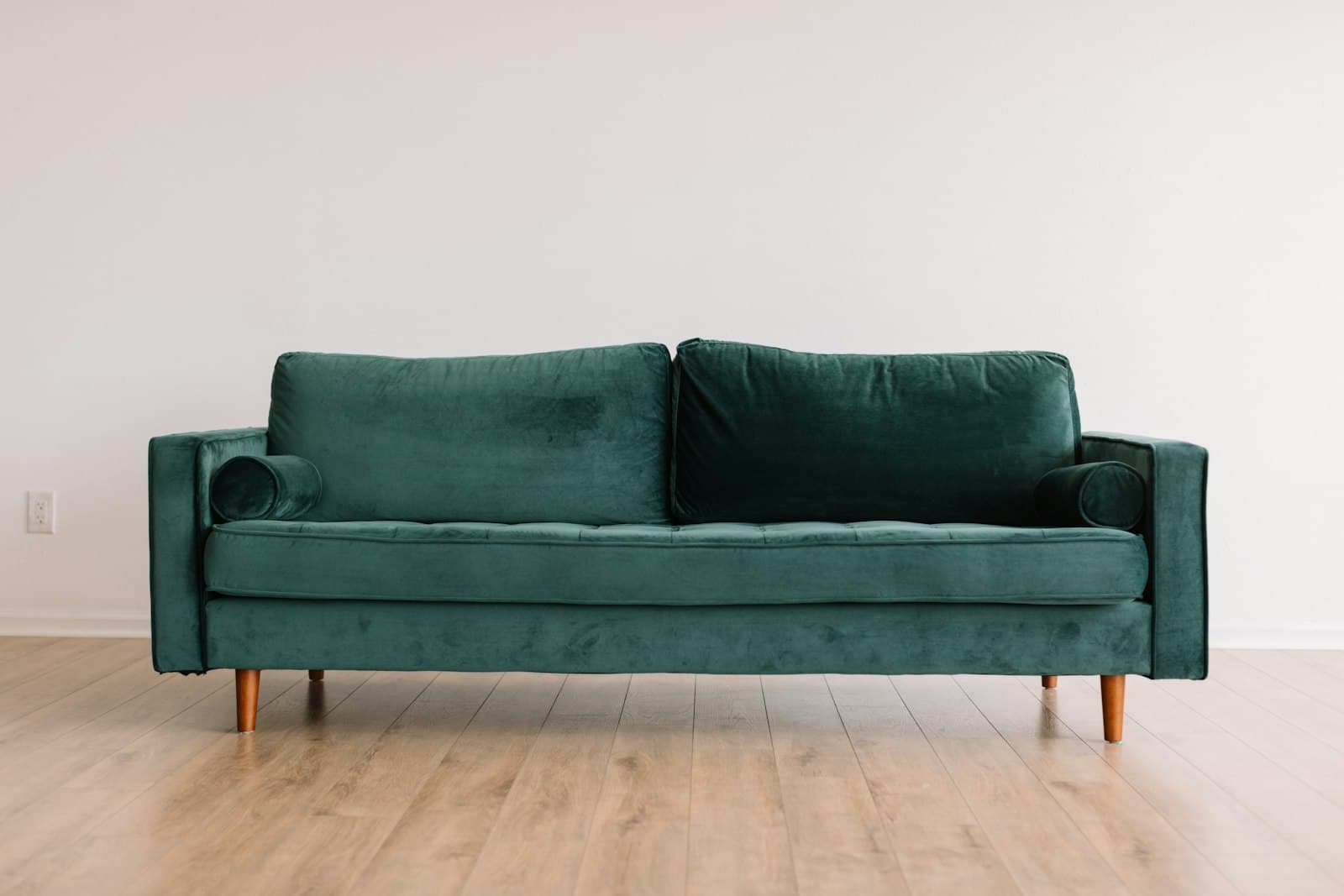 Forest green velvet three-seater sofa on light oak floor